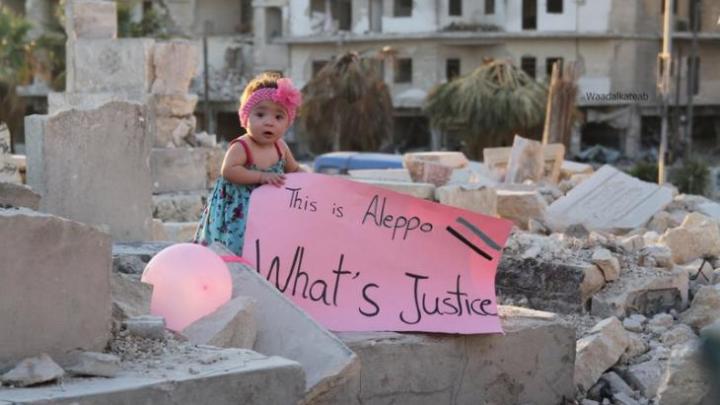 suriye'de yıkılmış evlerin arasında küçük bir kız